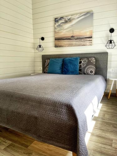 a bedroom with a large bed with blue pillows at Pilkas Namelis - Namelių nuoma Šventojoje in Šventoji
