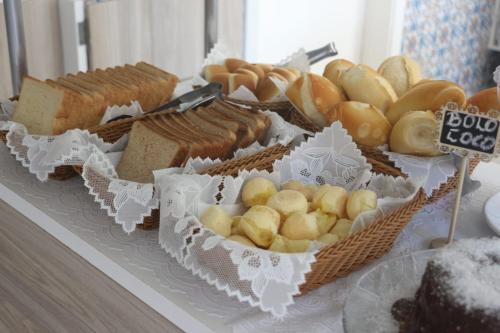 a table with baskets of bread and different types of bread at Pousada Ilha das Conchas in Guarujá