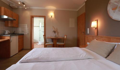 a bedroom with a white bed and a kitchen at Hofgut Langenborn Wohnen auf Zeit möblierte Apartments Aschaffenburg Alzenau Frankfurt in Schöllkrippen