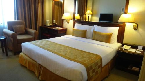 バンコクにあるアーノマ ホテル バンコク- SHA Plusの大きなベッドと椅子が備わるホテルルームです。