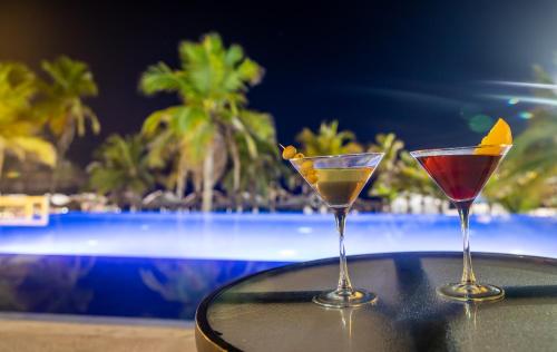 two martini glasses sitting on a table next to a pool at Emporio Acapulco in Acapulco