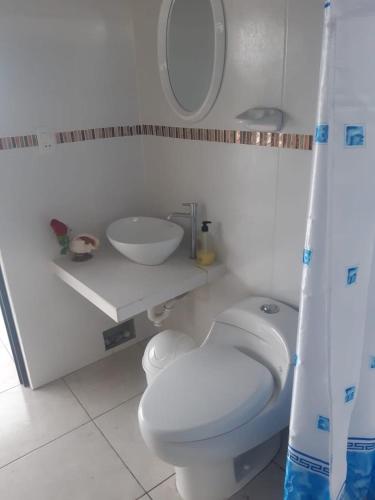 a bathroom with a white toilet and a sink at MarAzul, Casa grade familiar en Zorritos in Zorritos