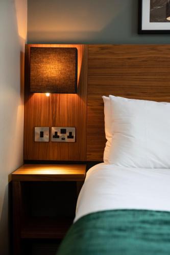 a bedroom with a bed with a wooden head board at The Oatlands Chaser by Innkeeper's Collection in Weybridge