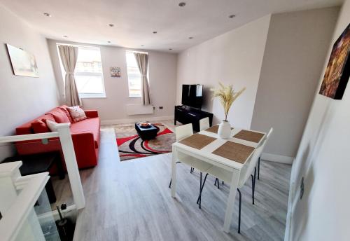 a living room with a table and a red couch at Modern Maisonette 2 Bedrooms Newly Renovated in Bournemouth