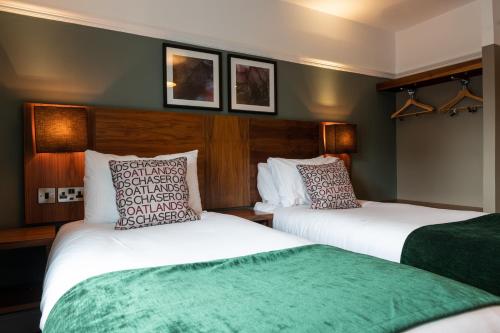 two beds in a room with green and white at The Oatlands Chaser by Innkeeper's Collection in Weybridge