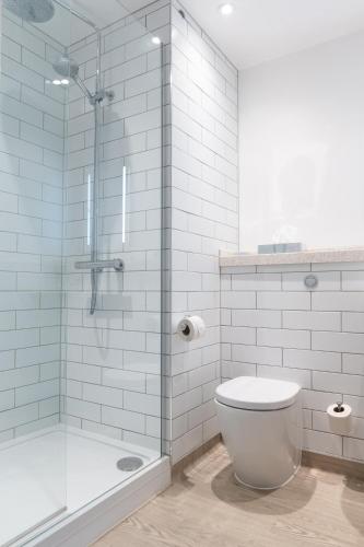 a bathroom with a toilet and a glass shower at The Oatlands Chaser by Innkeeper's Collection in Weybridge