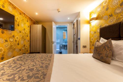 ein Schlafzimmer mit einem großen Bett mit gelben Wänden in der Unterkunft Hotel Shepherds Bush London in London