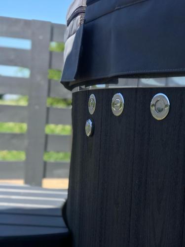 a black trash can sitting next to a fence at Pilkas Namelis - Namelių nuoma Šventojoje in Šventoji