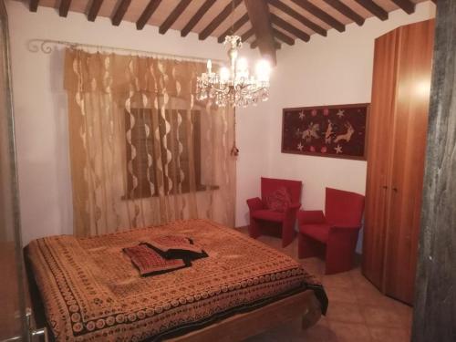 - une chambre avec un lit, un lustre et des chaises rouges dans l'établissement Confortevole locale, à Rosignano Marittimo