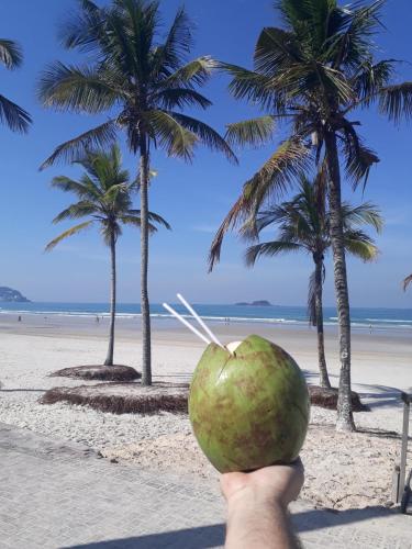 a person holding a coconut in front of a beach at Pousada Ilha das Conchas in Guarujá