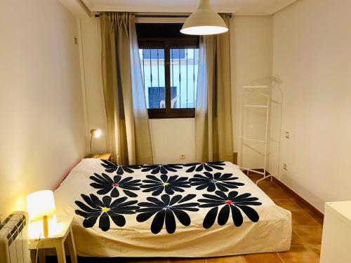 a bedroom with a bed with a black and white blanket at CÓMODO APARTAMENTO RURAL in Torrelaguna