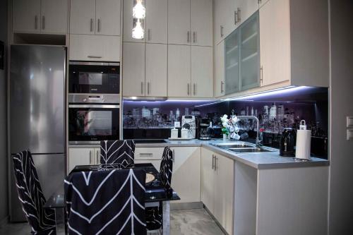 a kitchen with white cabinets and black and white appliances at Athens Nautical Flat in Piraeus