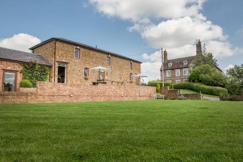 een groot bakstenen huis met een grasveld bij The Granary at Fawsley in Daventry