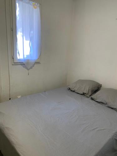 un lit blanc dans une chambre avec une fenêtre dans l'établissement APPARTEMENT PALAVAS LES FLOTS AVEC JARDIN et PISCINE, à Palavas-les-Flots