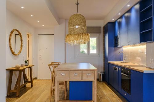 una cocina con armarios azules y una lámpara de araña en Dekalo Seaside Villa, Kriopigi en Kriopigi