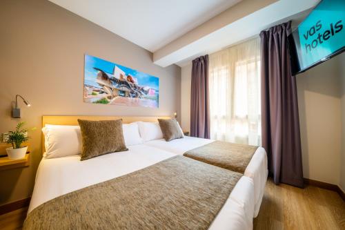 a hotel room with a large bed and a flat screen tv at Hotel Vas Vitoria AutoCheckIn in Vitoria-Gasteiz
