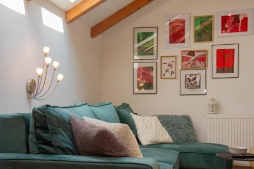 a living room with a green couch and pictures on the wall at Apartman Park in Zlatibor