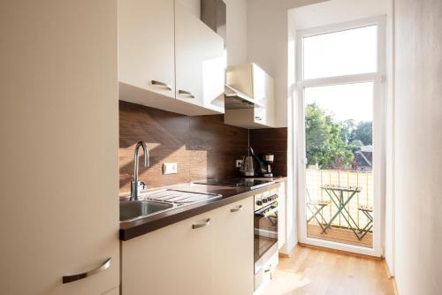 a kitchen with white cabinets and a sink and a window at City-Apartments Graz in Graz
