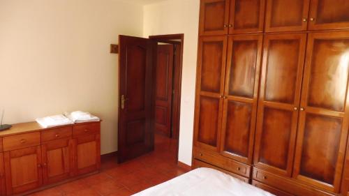 1 dormitorio con armarios de madera, 1 cama y vestidor en GBT Quartos en Sines