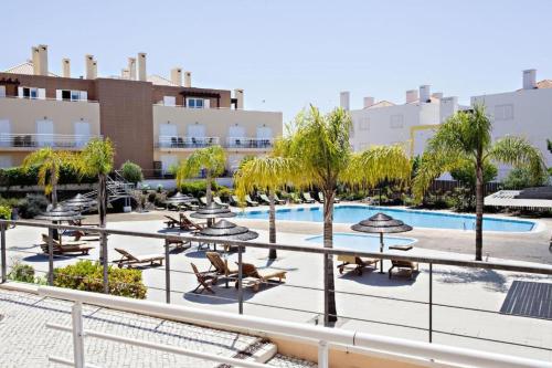 ein Resort mit einem Pool, Liegestühlen und Bäumen in der Unterkunft Apartamento Duplex - Cabanas Garden in Tavira