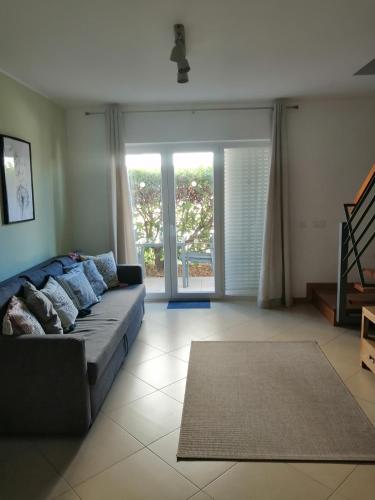 a living room with a couch and a large window at Apartamento Duplex - Cabanas Garden in Tavira