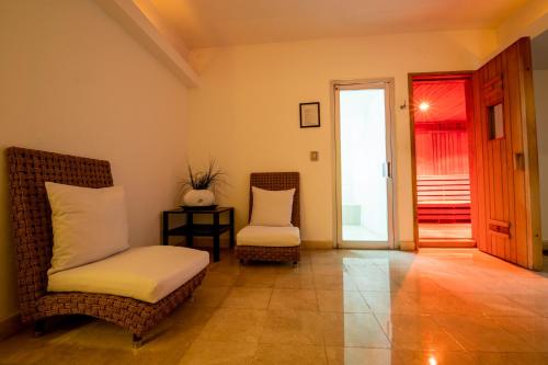 a room with a bed and two chairs and a door at Emporio Acapulco in Acapulco