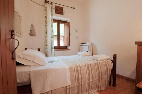 um quarto com uma cama com lençóis brancos e uma janela em Villa San Marco - Casa esclusiva nel Sinis em San Giovanni di Sinis