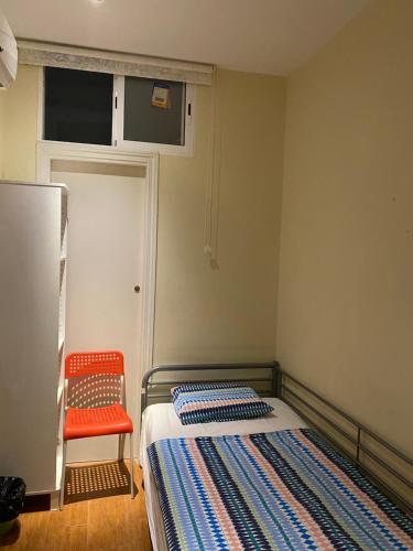 1 dormitorio pequeño con 1 cama y 1 silla roja en Hostal Granvia 628, en Barcelona