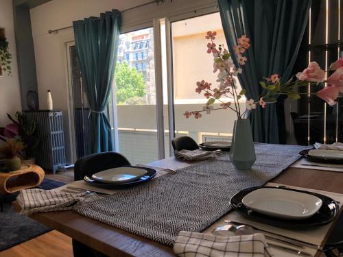 einem Esstisch mit Tellern und einer Vase aus Blumen in der Unterkunft Magnifique T3 Dans Une Résidence Au Centre De Toulon in Toulon