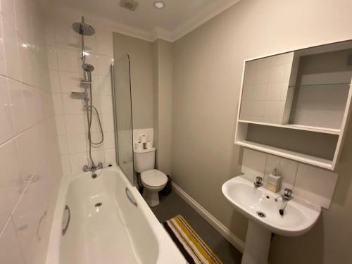 a bathroom with a tub and a sink and a toilet at Crofton House Garden Apartment in Ryde