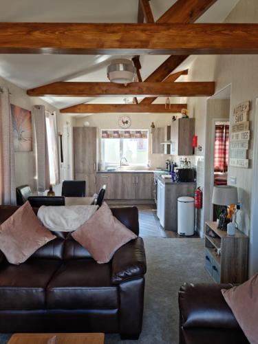 a living room with a leather couch and a kitchen at Captivatingly Stunning 2-Bed Chalet in Bridlington in Bridlington