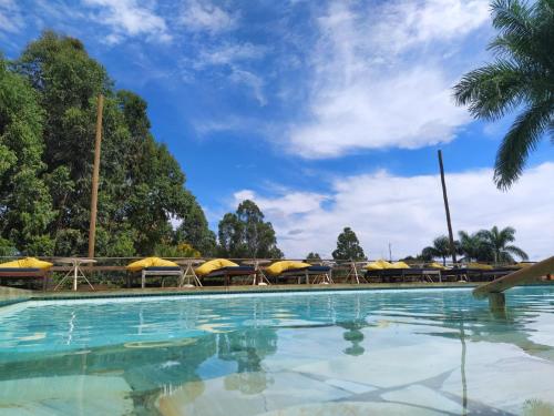 una piscina con mesas y sombrillas en Village Resort en Jaboticatubas