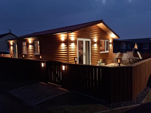 a house with lights on the deck at night at Captivatingly Stunning 2-Bed Chalet in Bridlington in Bridlington