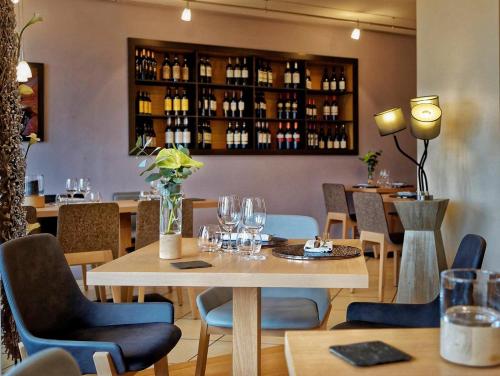 un restaurante con mesa, sillas y botellas de vino en Hotel Residence Bellevue, en Cambo-les-Bains