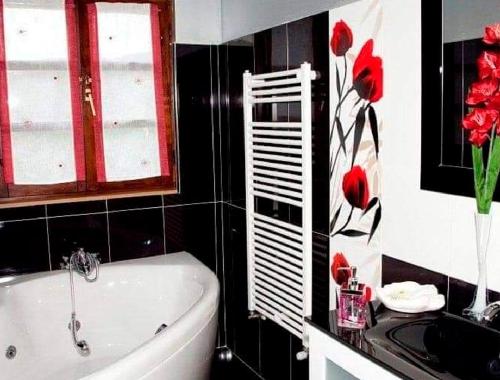 a bathroom with a tub and red flowers on the wall at La Riguera De Ucieda in Ucieda de Arriba