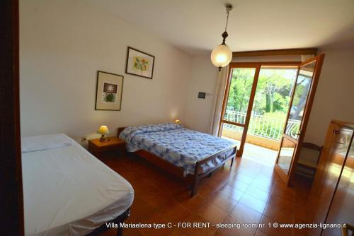 リニャーノ・サッビアドーロにあるLignano Riviera Spaciousのベッドルーム1室(ベッド1台付)、スライド式ガラスドアが備わります。