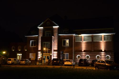 a building with cars parked in front of it at night at Hôtel la Régie in Briey