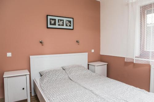 1 dormitorio con 1 cama blanca y paredes de color naranja en Négy évszak apartmanház, en Mezőkövesd