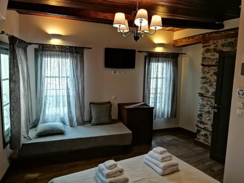 a room with a bed and a tv and windows at RiverBed Traditional Guest House in Litochoro