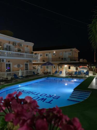 a large swimming pool in front of a hotel at night at Two Brothers Studios Tsilivi Zakynthos in Tsilivi