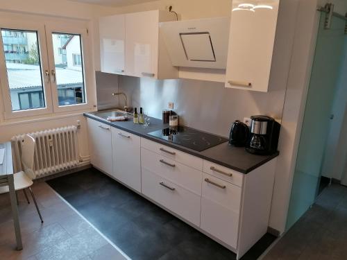 a kitchen with white cabinets and a sink and a window at Ferienwohnung Ratoldi in Radolfzell am Bodensee