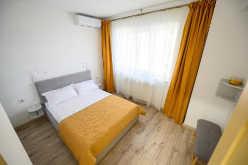 um pequeno quarto com uma cama e uma janela em Sunset Lake Apartament Mamaia em Mamaia