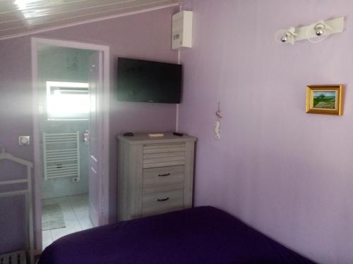 een slaapkamer met een bed, een dressoir en een televisie bij Chez Gigi in Merville-Franceville-Plage