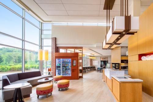 a living room with a couch and tables and windows at Hyatt Place at The Hollywood Casino Pittsburgh South in Washington
