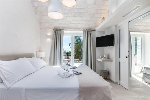 ein weißes Schlafzimmer mit einem großen Bett und einem Fenster in der Unterkunft Villa Ludovica in Ostuni