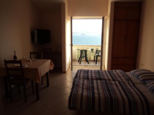 a bedroom with a bed and a table and a view of the ocean at Apartments Delfini in Sveti Filip i Jakov