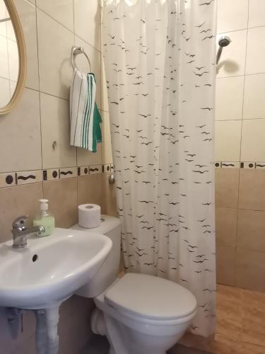 a bathroom with a toilet and a sink and a shower curtain at Guest House 51 in Kranevo
