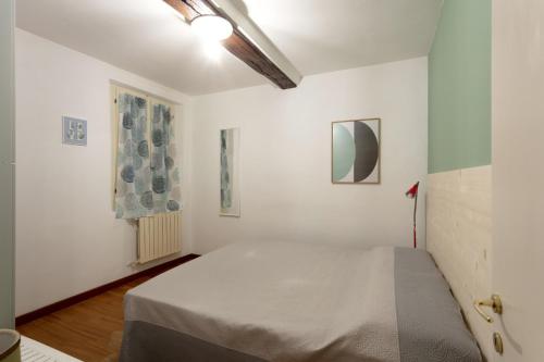 Un dormitorio con una cama en una habitación blanca. en Rua Freda Apartments, en Módena