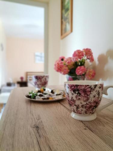 a table with two cups and a plate with flowers at Guest House 51 in Kranevo
