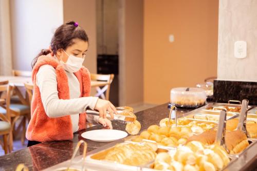 a woman in a mask preparing food at a buffet at Hotel Mamma Mia in Aparecida